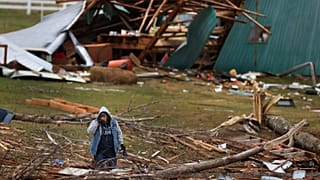 A woman searches for valuables amidst the remnants of a home on Saturday, Dec.11, 2021, on Highway F in Defiance, Mo. 
