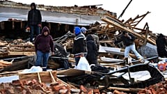 A family digs through the remains of their apartment in Mayfield, Ky., Saturday, Dec. 11, 2021. 