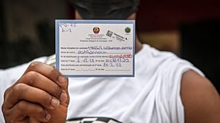 Jovem exibe cartão de vacinação pouco depois de tomar a primeira dose da vacina Vaxzevria, Maputo, Moçambique