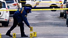 A police officer collects evidence markers at the scene of a shooting