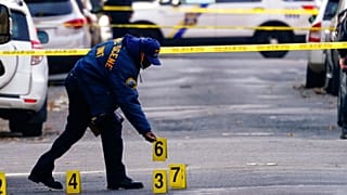 A police officer collects evidence markers at the scene of a shooting