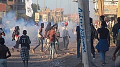 متظاهرون سودانيون ينظرون إلى قوات الأمن وهي تطلق قنابل الغاز المسيل للدموع لتفريق حشد في العاصمة الخرطوم ، في 6 ديسمبر 2021.