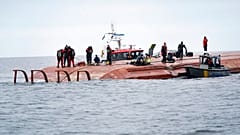 Des plongeurs se préparent à chercher les deux personnes disparues, sur le cargo danois retourné après la collision, au large de la Suède