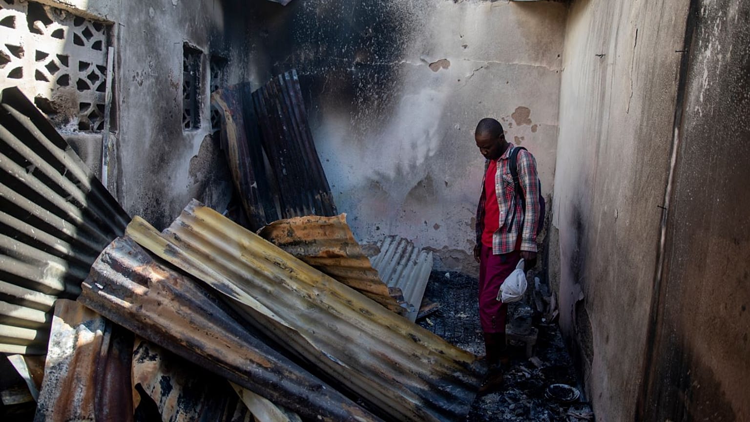 A resident looks at collapsed tin roof inside a home damaged by the explosion in Cap-Hatien.
