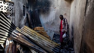 A resident looks at collapsed tin roof inside a home damaged by the explosion in Cap-Hatien.