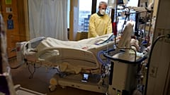 Steve Grove, a chaplain at Hennepin County Medical Center, prays in a COVID-19 patient's room, Friday, Dec. 10, 2021, in Minneapolis. 