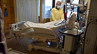 Steve Grove, a chaplain at Hennepin County Medical Center, prays in a COVID-19 patient's room, Friday, Dec. 10, 2021, in Minneapolis. 