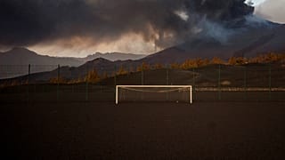 Un campo de fútbol está cubierto por cenizas negras mientras la lava fluye desde el volcán, en la isla canaria de La Palma, España, el lunes 6 de diciembre de 2021