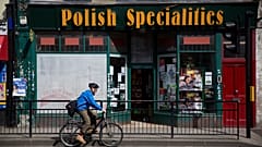 In this Tuesday, April 5, 2016 file photo, a man cycles past a Polish Specialties shop in London. 