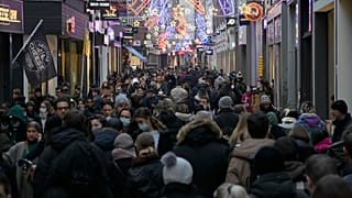 Crowds of people walk down a street on the last Saturday before Christmas in Amsterdam, the Netherlands