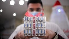 A member of the medical staff at a COVID-19 vaccination center holds a present box made of empty vaccine containers in Bucharest, Romania, Dec. 6, 2021.
