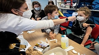 A medical staff takes the temperature to a child in a vaccine center in Sélestat, eastern France, Dec. 21, 2021. 