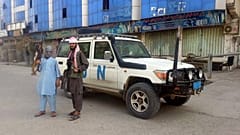 Afganistan'ın kuzeyindeki Kunduz kentinde bir BM aracı önünde poz veren Taliban savaşçıları (arşiv) 