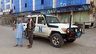 Afganistan'ın kuzeyindeki Kunduz kentinde bir BM aracı önünde poz veren Taliban savaşçıları (arşiv) 