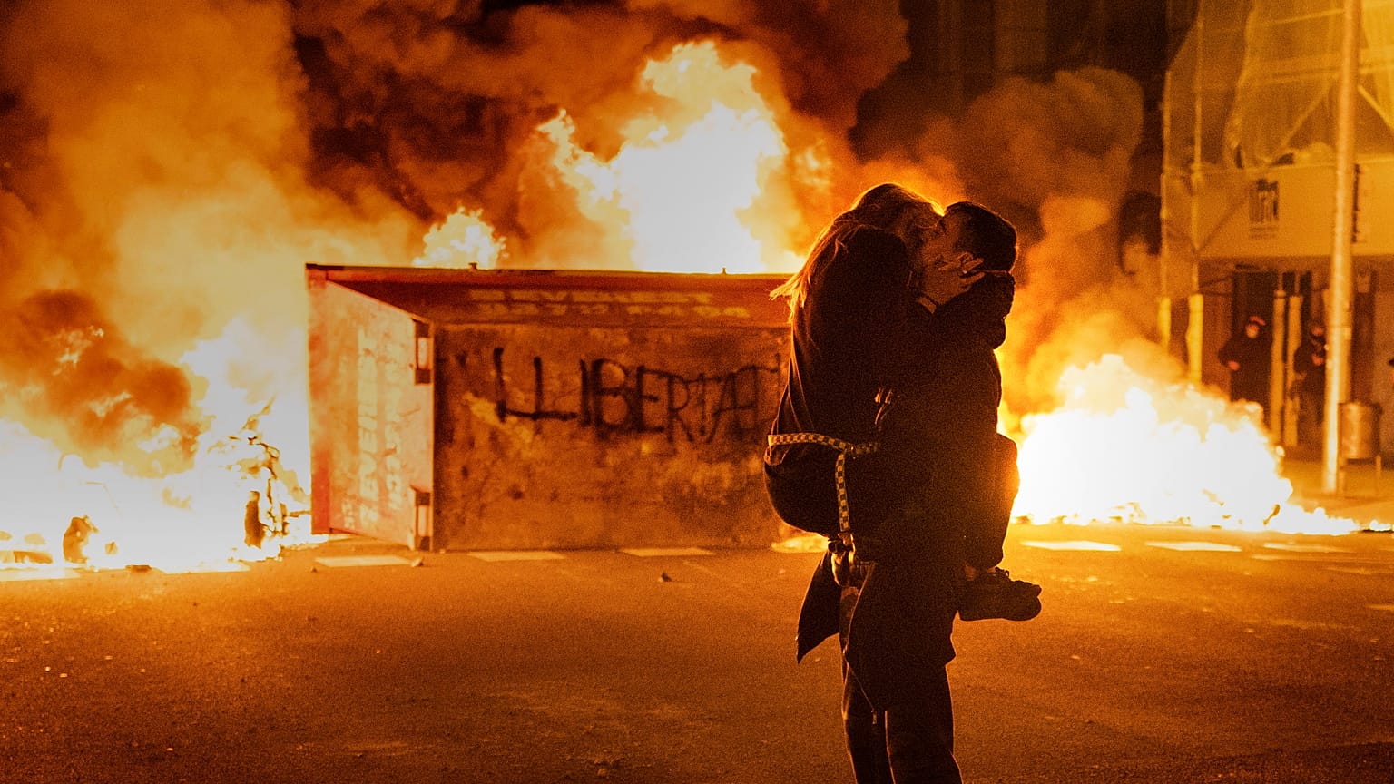 A couple kiss during clashes with police following a protest condemning the imprisonment of rap singer Pablo Hasél in Barcelona, Spain. February 2021 