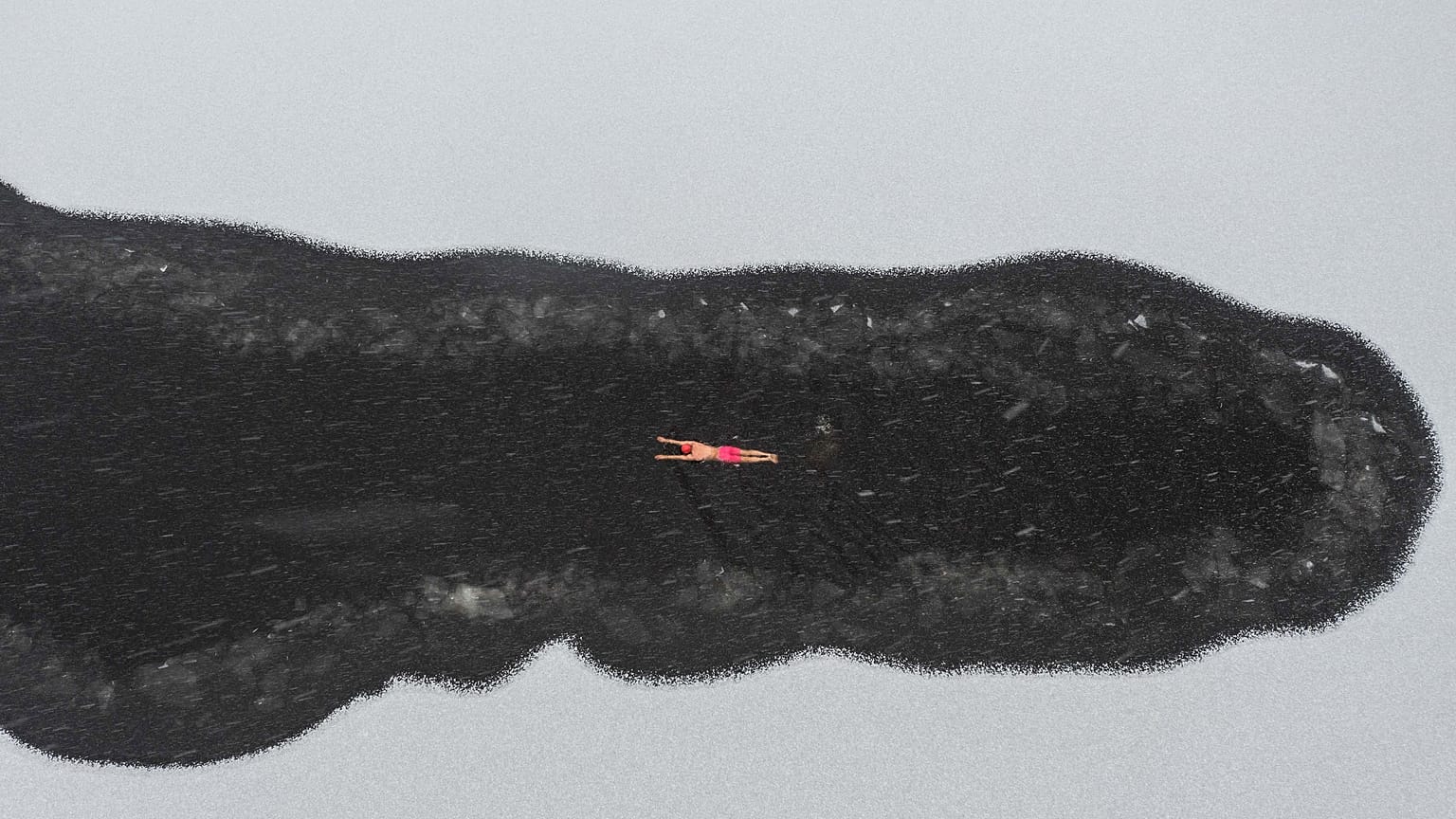 A winter swimming enthusiast swimming in a partly frozen lake during snowfall at a park in Shenyang, in northeastern China's Liaoning province. November 2021