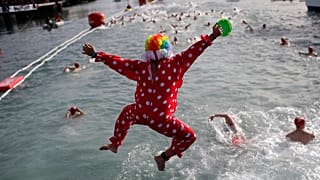 Persona vestida de payaso salta al Mediterráneo en Barcelona mientras participa en la Copa Nadal, una tradicional competición de natación que se celebra cada 25 de diciembre.