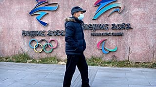 Ein Mann vor den Logos der Olympischen und Paralympischen Spiele 2022
