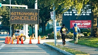 People walk past a sign announcing Astroworld is canceled outside NRG in Houston on Nov. 6, 2021. 