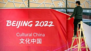 A worker takes down coverings around an exhibit on Chinese culture at a commercial plaza at the Winter Olympic Village in Beijing, Friday, Dec. 24, 2021.