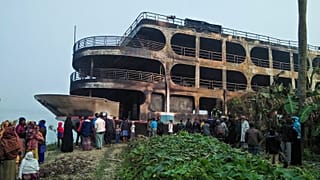 Villagers look at a burnt-out ferry after it caught on fire killing at least 37 people in Jhakakathi, 250 kilometres south of Dhaka, on December 24, 2021.