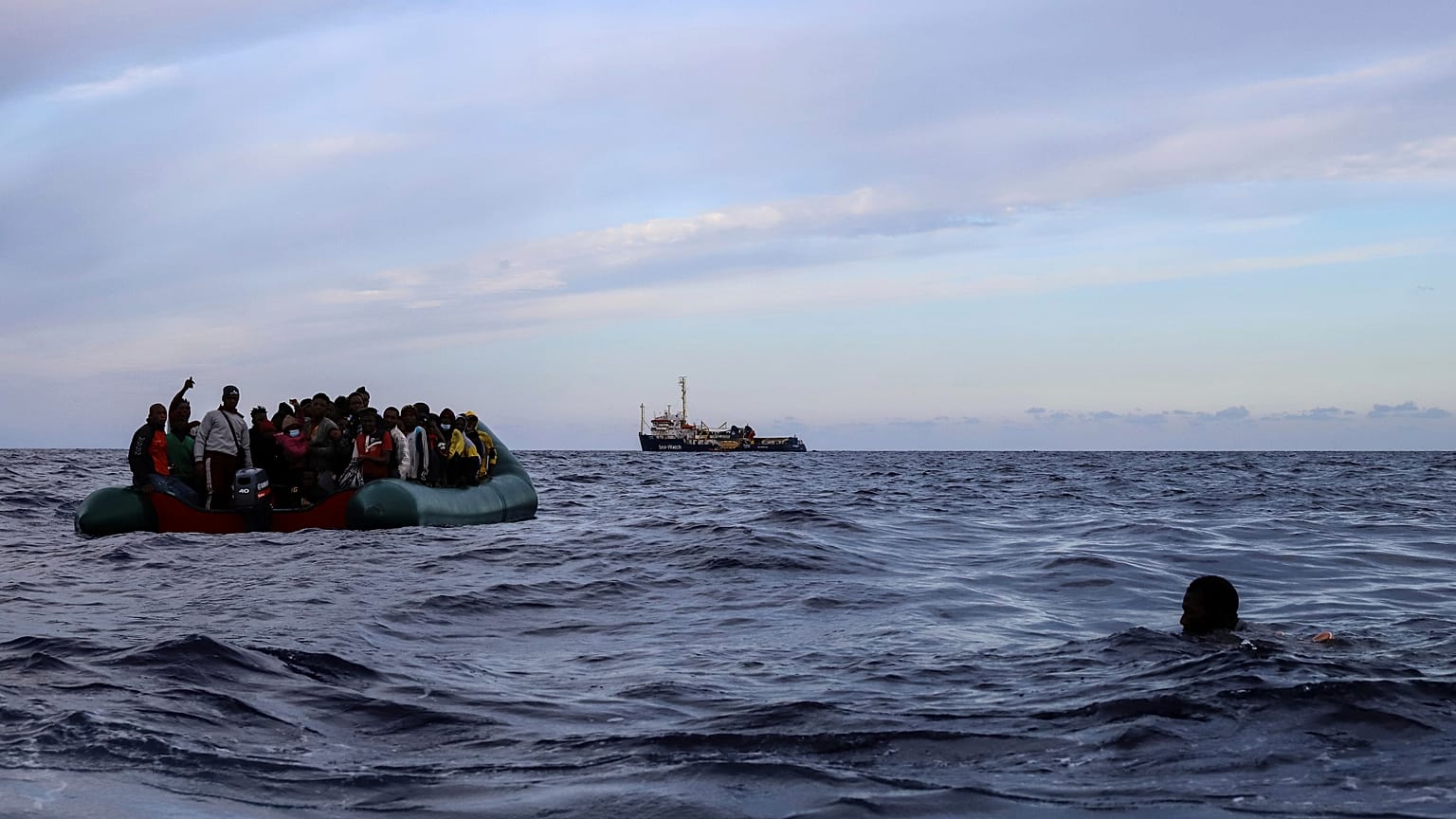 A migrant who was aboard a precarious rubber boat with others jumps to the water as they are rescued around 35 miles away from Libya, in Libyan SAR zone, Oct. 18, 2021