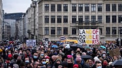A man holds a sign which reads 'Land of double standards' as he protests with other artists during a demonstration in Brussels