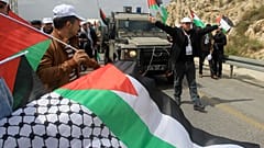 متظاهرون فلسطينيون يعترضون سيارة جيب عسكرية لقوات الأمن الإسرائيلية خلال مظاهرة لإحياء يوم الأرض، في قرية برقة بالضفة الغربية، غربي نابلس، في 30 مارس 2016