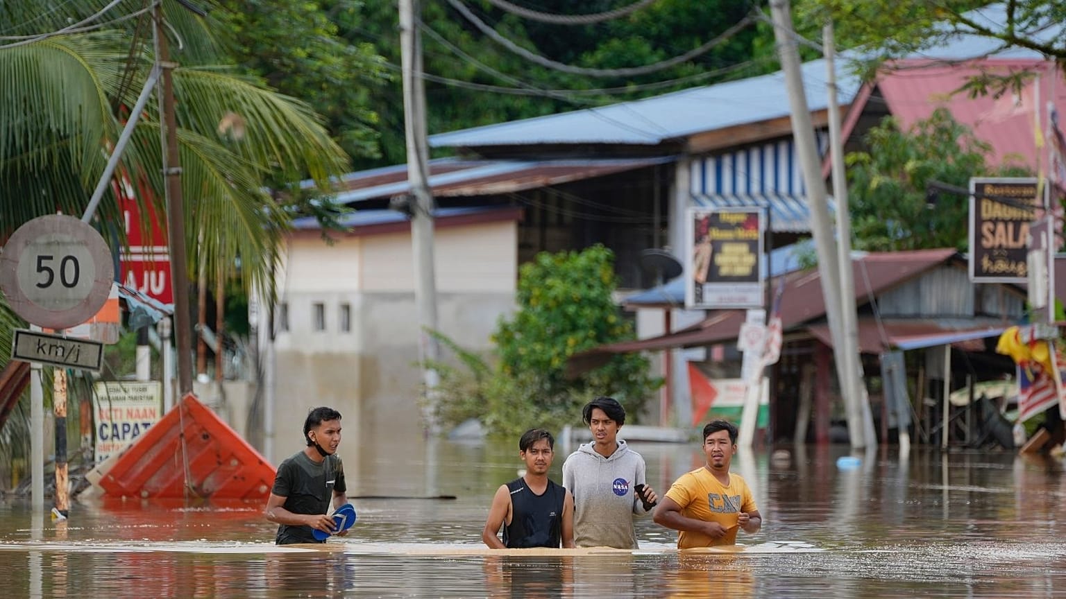 People wade through a flooded road outside Kuala Lumpur on 19 December.