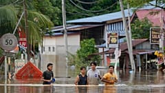 People wade through a flooded road outside Kuala Lumpur on 19 December.