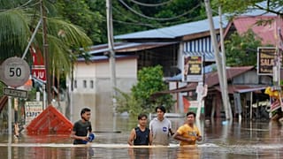 People wade through a flooded road outside Kuala Lumpur on 19 December.