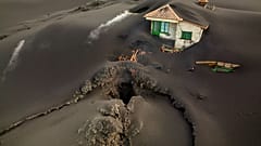 A fissure is seen next to a house covered with ash on the Canary island of La Palma