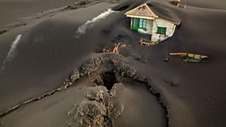 A fissure is seen next to a house covered with ash on the Canary island of La Palma