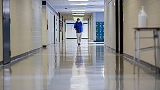 A middle school principal walks the empty halls of his school as he speaks with one of his teachers to get an update on her COVID-19 symptoms, Aug., 20, 2021, in Wrightsville.
