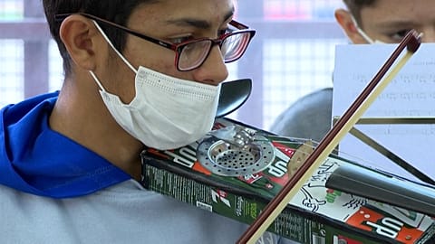 Young man playing recycled instrument.