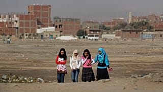 فتيات مصريات يمشين عبر أرض نفايات في حي حلوان الذي تقطنه الطبقة العاملة في القاهرة، مصر، الخميس 27 يناير 2011.