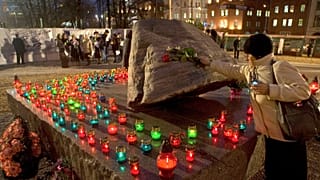 Egy nő virágot helyez el az áldozatok emlékművénél a Lubjankánál, a volt KGB főhadiszállásánál