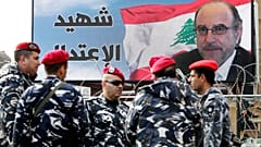 ناصر من الجيش اللبناني يقفون بجانب ملصق محمد شطح، الذي اغتيل في انفجار سيارة مفخخة، خلال جنازته في ساحة الشهداء في بيروت، لبنان، الأحد 29 ديسمبر/كانون الأول 2013. 