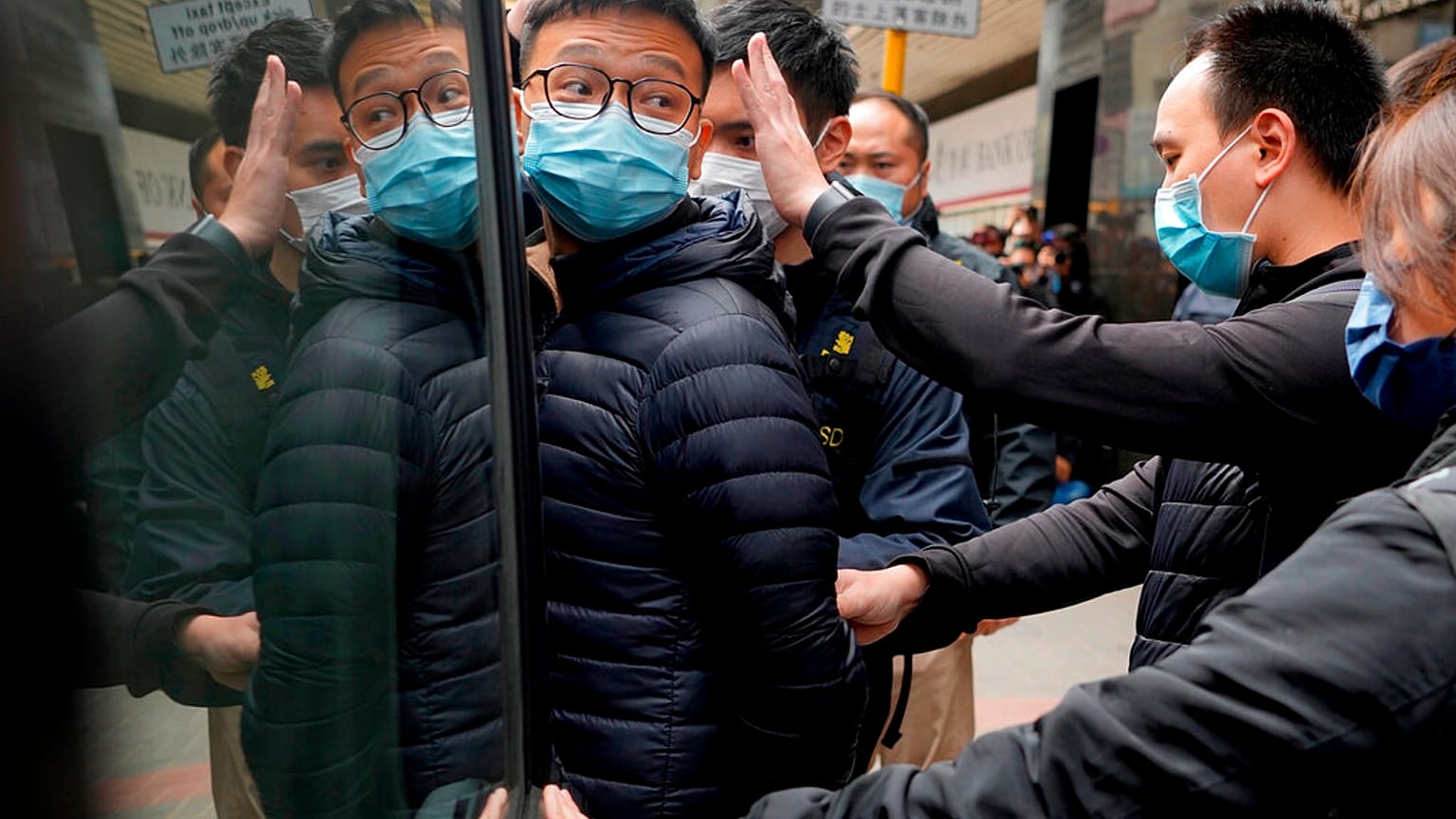 Le rédacteur en chef de Stand News, Patrick Lam, escorté par des policiers après une perquisition dans son bureau à Hong Kong