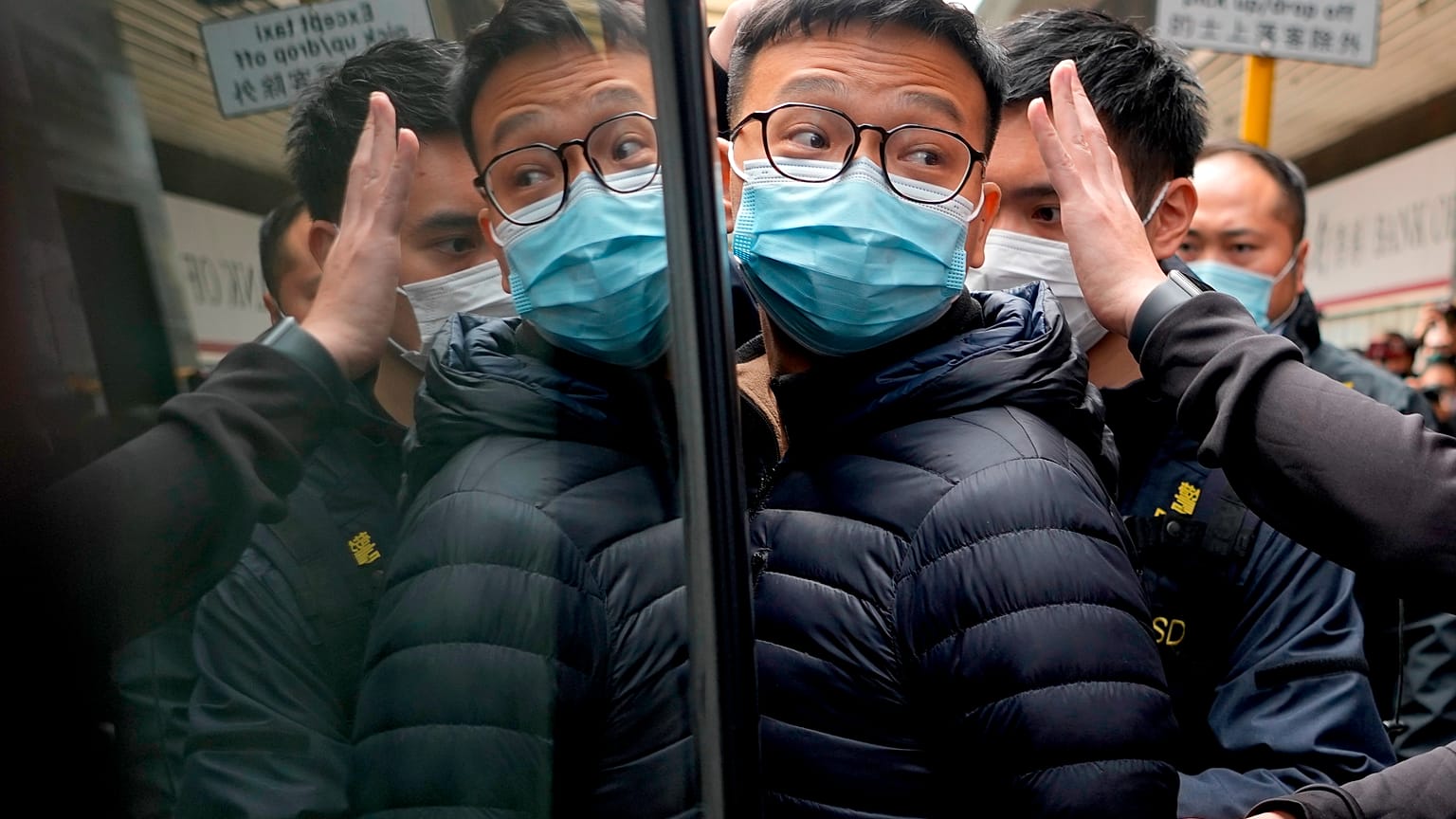 El editor de Stand News Patrick Lam, escoltado por agentes de policía a una furgoneta, 29/12/2021, Hong Kong, China