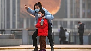 Une femme et un enfant, portant des masques, à Pékin, le 28 novembre 2021