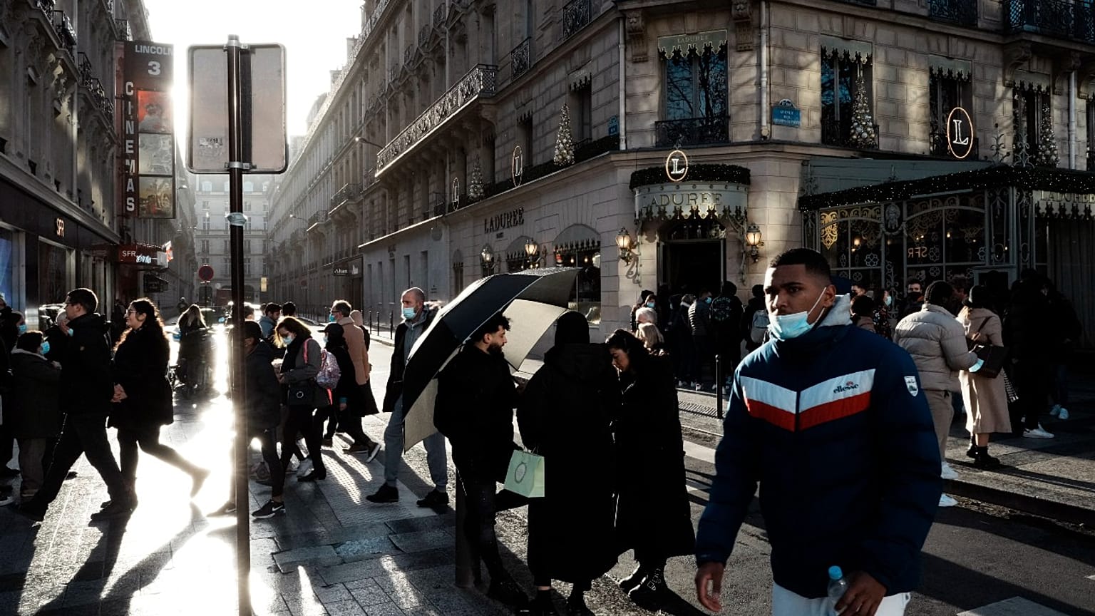 People walk down the Champs Elysees avenue, in Paris, Tuesday, Dec. 28, 2021.