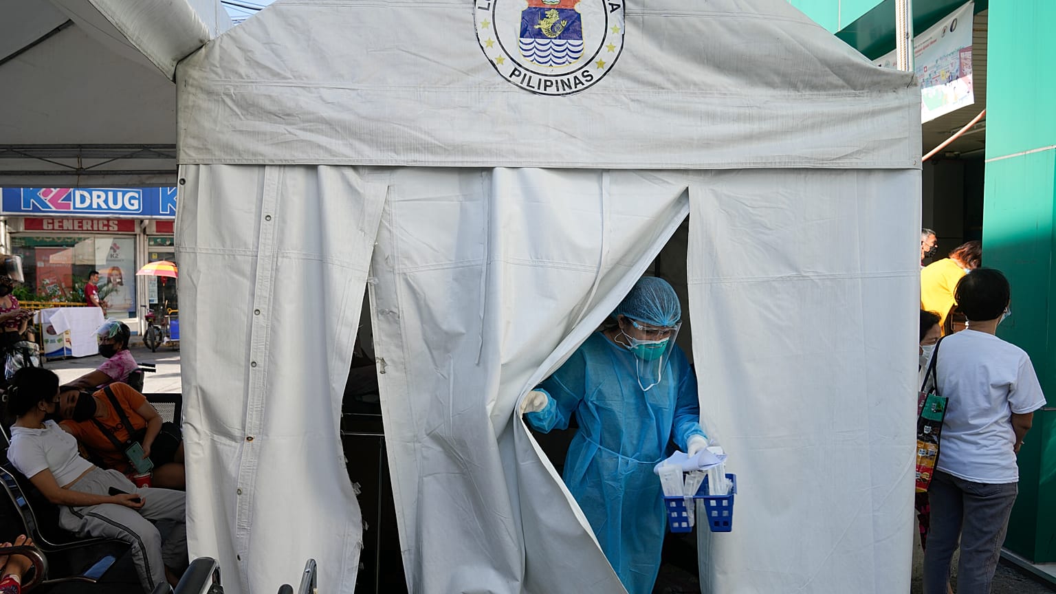Medical Technologist Erika Alvarado comes out of a tent after she performs a COVID-19 test on a patient outside a hospital in Manila, Philippines on Friday, Dec. 24, 2021.