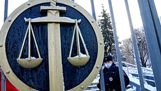 A police officer guards a an entrance of the Moscow Court where supporters of the Memorial human rights group gather in Moscow, Russia, Wednesday, Dec. 29, 2021.