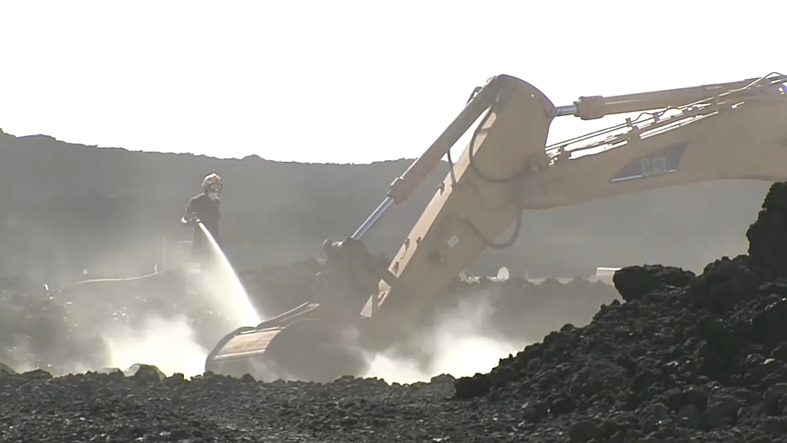 Pelleteuse en action et pompier arrosant la lave encore fumante, district de la Laguna, 29,décembre 2021
