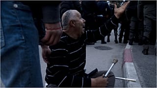 ناشط فلسطيني يصرخ على عناصر الشرطة الإسرائيلية بعد أن كسروا عكازيه خلال تظاهرة ضد إجلاء عائلات فلسطينية من منازلها في حي الشيخ جراح بالقدس الشرقية، 31 ديسمبر 2021