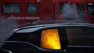 A firefighters truck parks by a burning car during a demonstration, Dec. 5, 2020 in Paris.