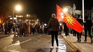 A woman with the old national flag stands in front of the parliament building in Skopje