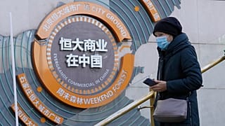 A woman passes by a display showing Evergrande's China commercial projects in Beijing, China, Tuesday, Dec. 7, 2021.