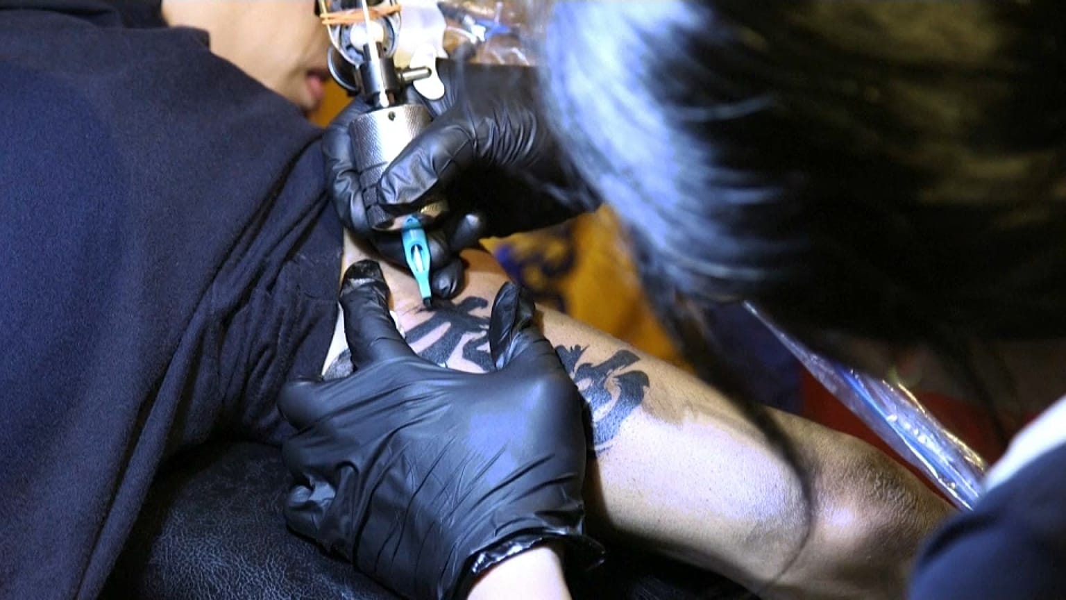 Un hombre se realiza un tatuaje en el brazo con tinta negra